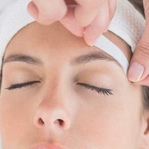 Woman getting waxing done on her eyebrows